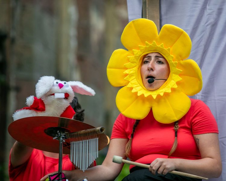 A rabbit and a sunflower drumming on stage